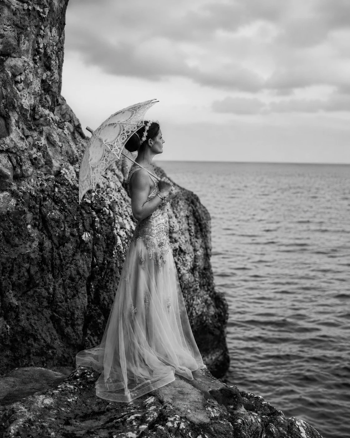 Mariée au bord de la mer avec une ombrelle